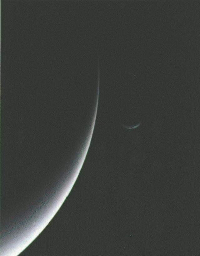 Частично освещенные Нептун и его луна Тритон.