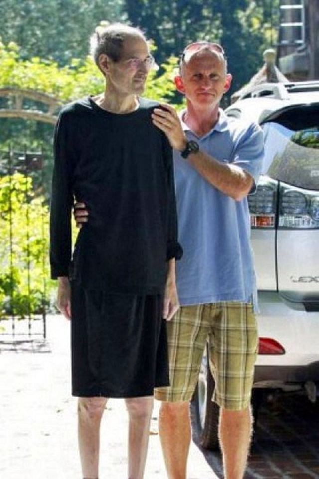 Друг помогает больному раком Стиву Джобсу дойти до машины у его дома в Калифорнии 26 августа 2011 года.