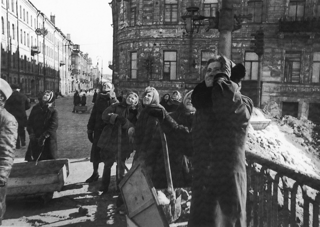 Женщины, занятые уборкой ленинградских улиц, наблюдают за воздушным боем над городом.