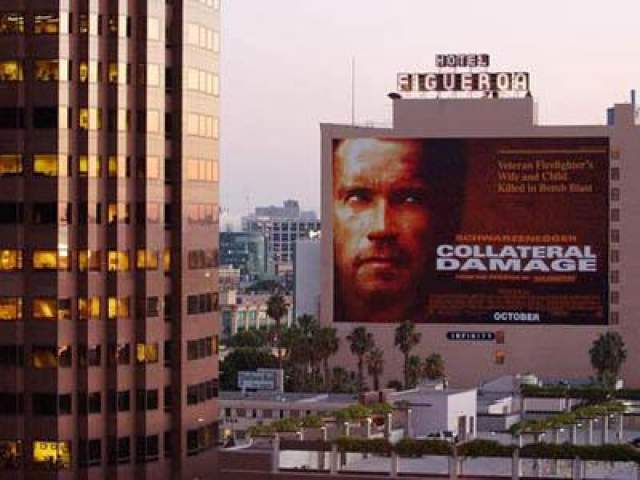 12 сентября 2001 года: на этом снимке, сделанном на следующий день после терактов 11 сентября, виден плакат, рекламирующий новый фильм с участием Арнольда Шварценеггера «Возмещение ущерба» рядом с офисным небоскребом в Лос-Анджелесе.